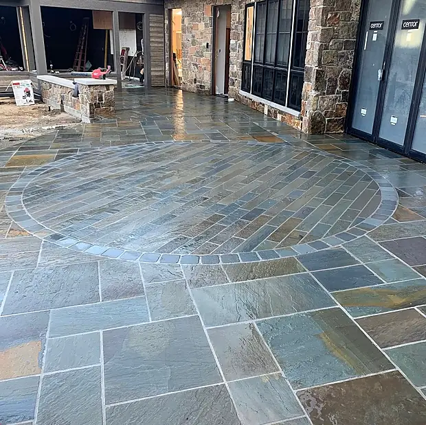 Natural bluestone patio laid in a random pattern with a circular herringbone inlay set into it