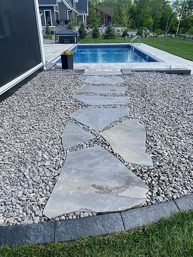 Irregular flagstone stepping stones set in decorative gravel leading to a pool deck