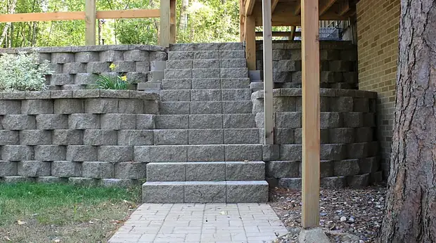 Curved segmental block retaining wall with a wide stair run leading up to a deck