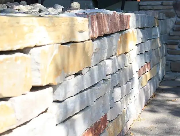 Close view of a dry-stacked natural stone wall showing layered color variation